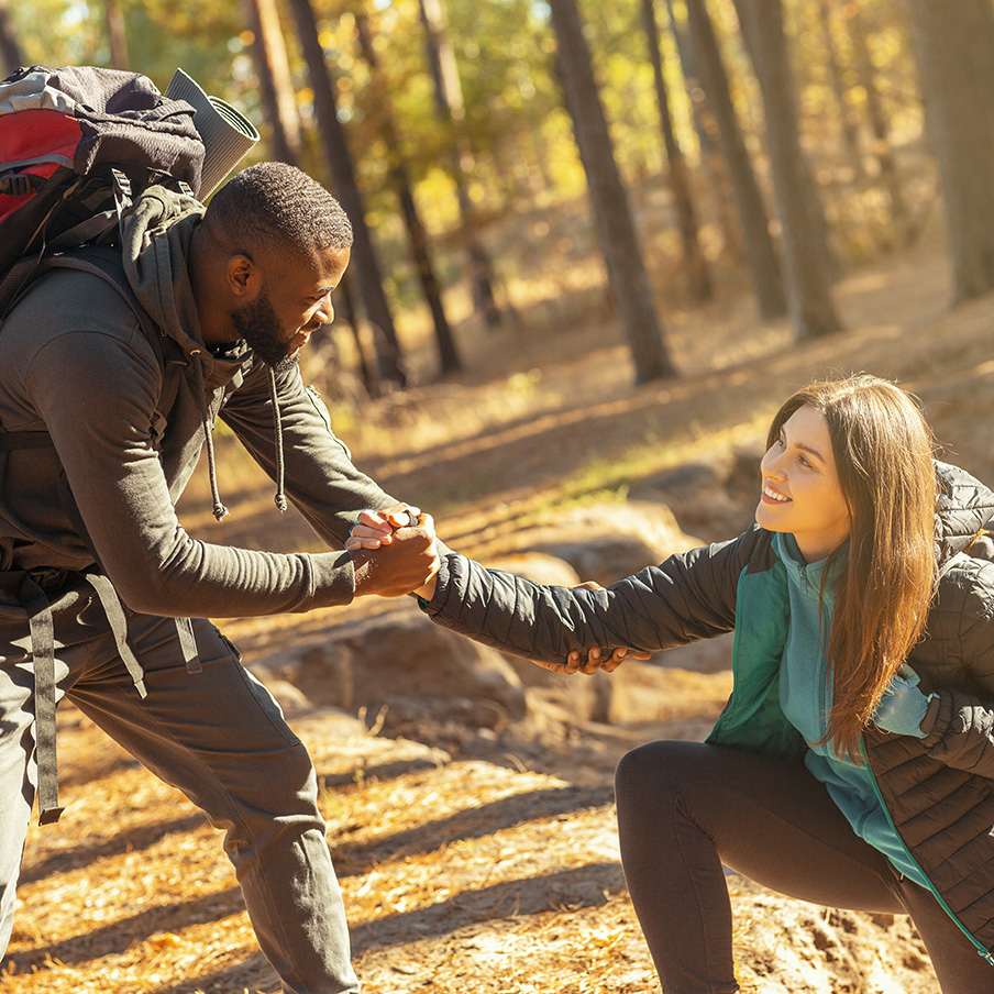 Black guy helping his girlfriend to climb up Teamwork